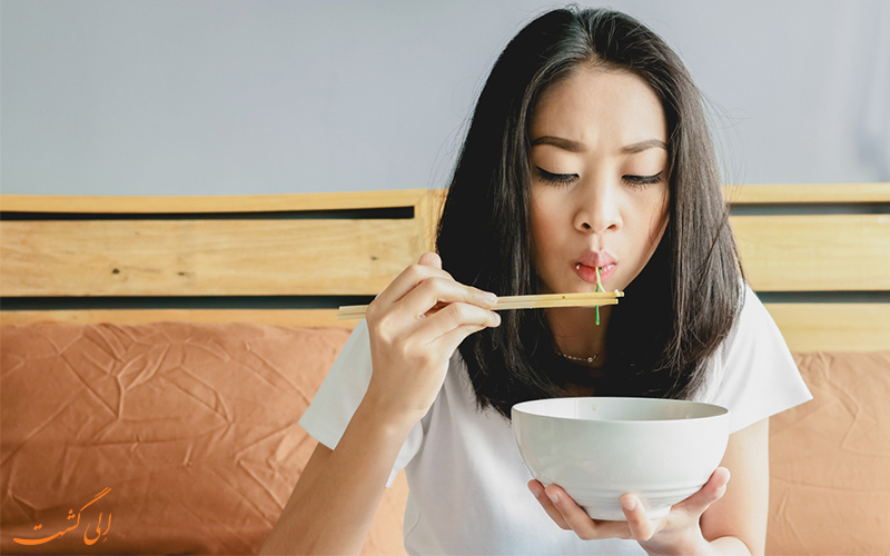 تصویر دختری چینی در حال غذا خوردن با چوب چاپستیک